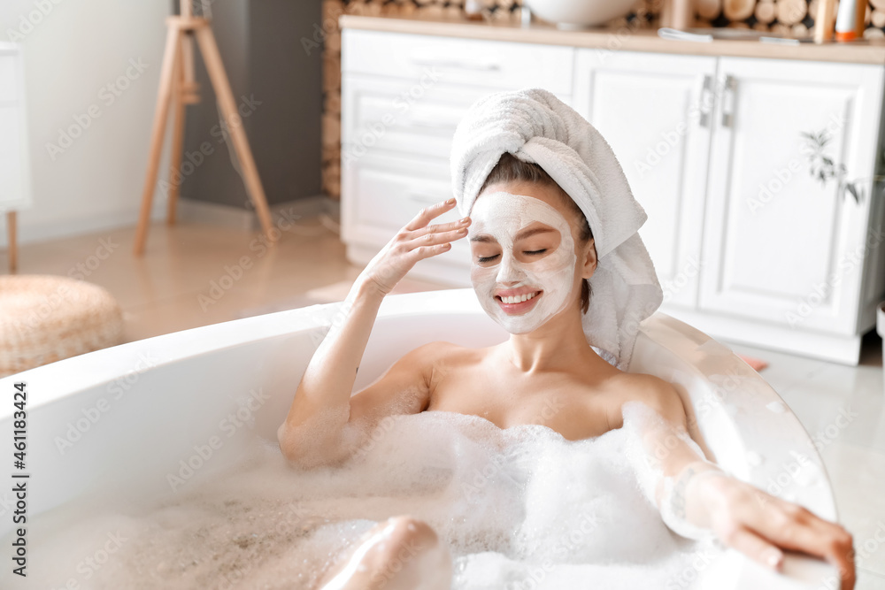 Young woman with facial mask taking relaxing bath at home