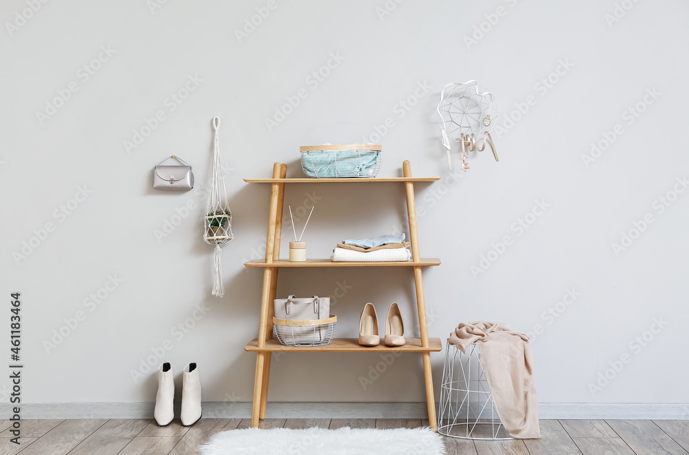 Wooden shelving unit with wardrobe organizers near light wall