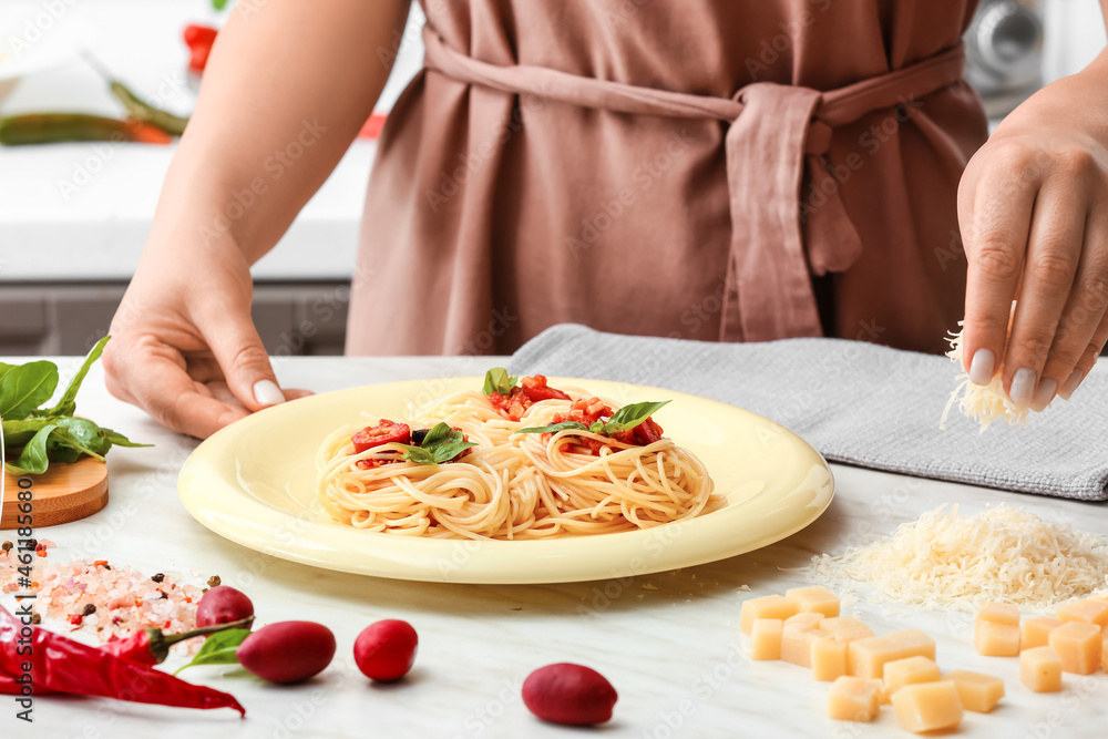 Woman preparing Pasta Puttanesca at kitchen table, closeup