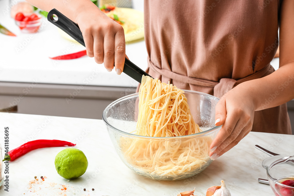 Woman preparing Pasta Puttanesca at kitchen table, closeup