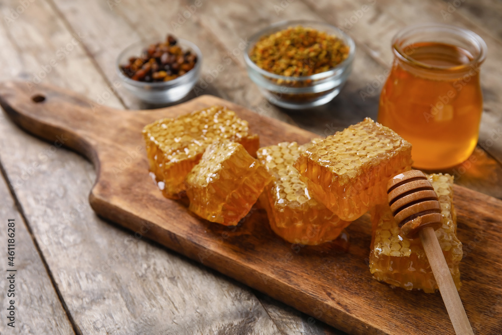 Board with honey combs on wooden background