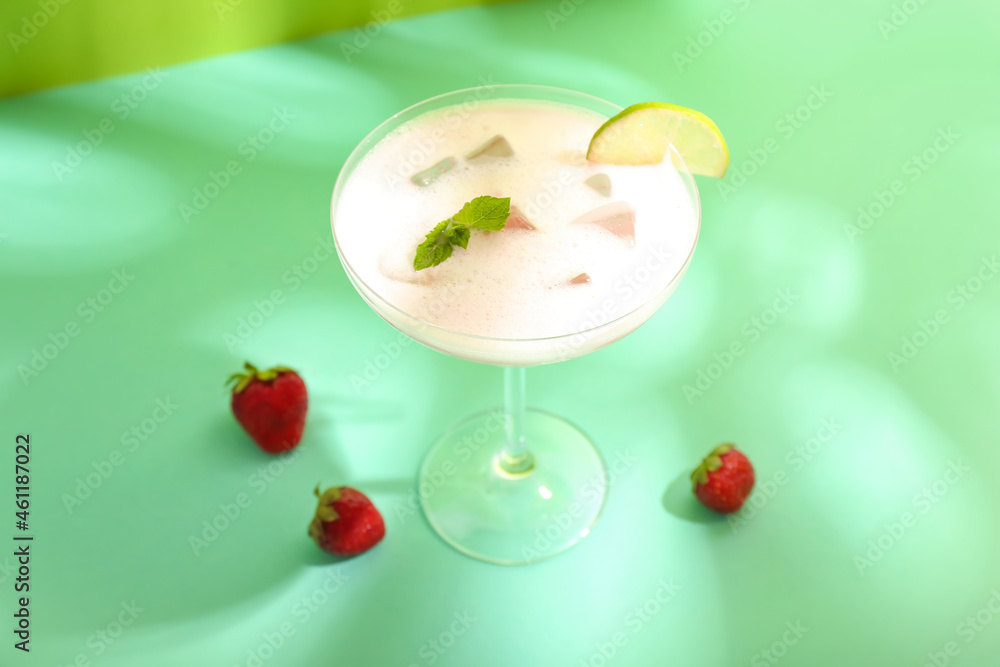 Glass of strawberry Pina Colada cocktail and berries on color background