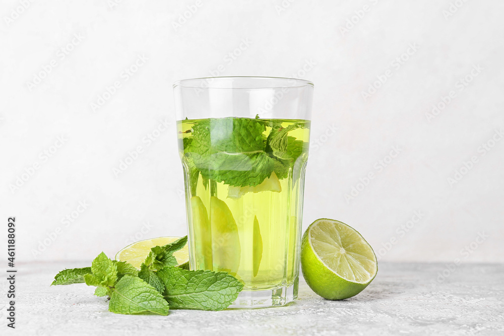 Glass of tasty mint tea with lime on white background