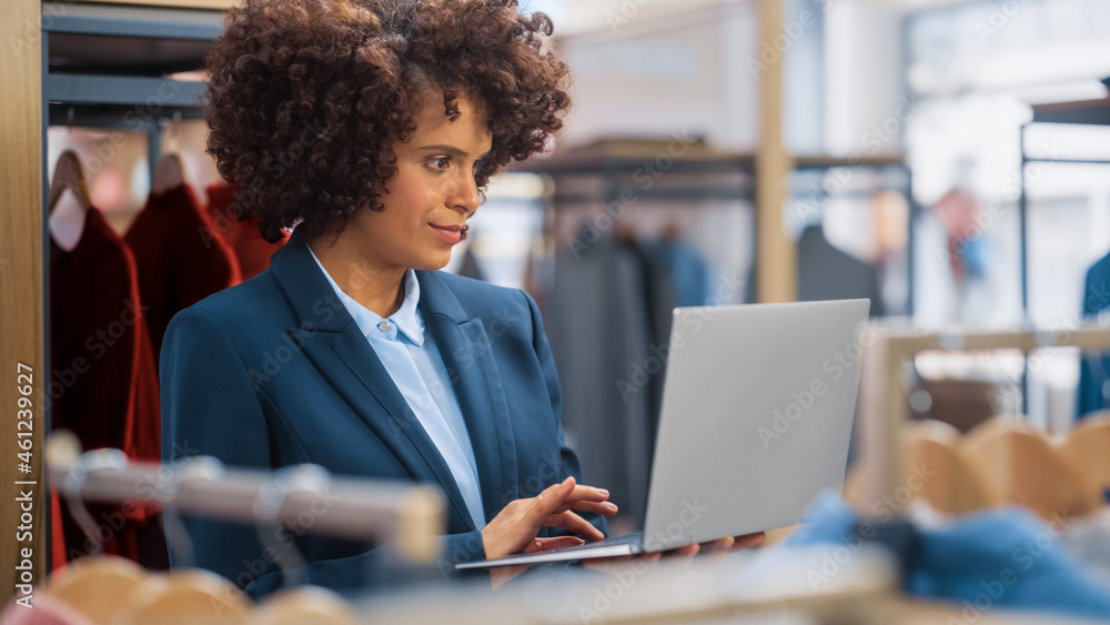 Clothing Store: Female Merchandising Manager Uses Laptop Computer To Create Stylish Fashion Collecti