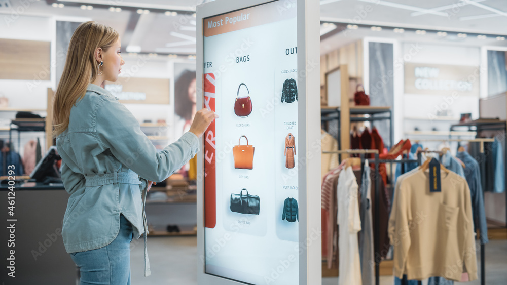 Beautiful Female Customer Using Floor-Standing LCD Touch Display while Shopping in Clothing Store. S