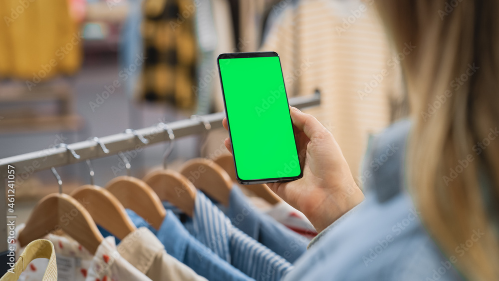 Clothing Store: Female Using Smartphone with Chroma Key Green Screen Display. Clothes Hanger with St