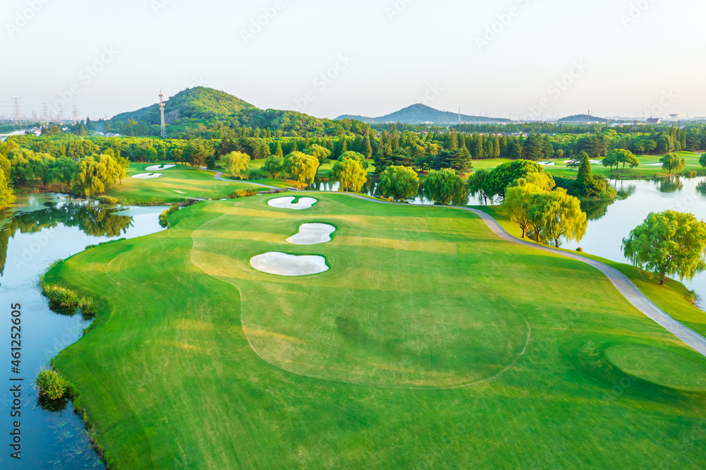 Aerial view of green lawn and forest on golf course.Green golf course scenery at sunset.