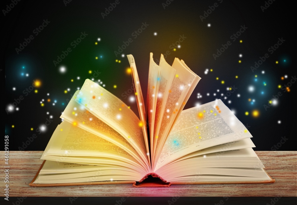 Magical image of open antique book on wooden table with glitter lights