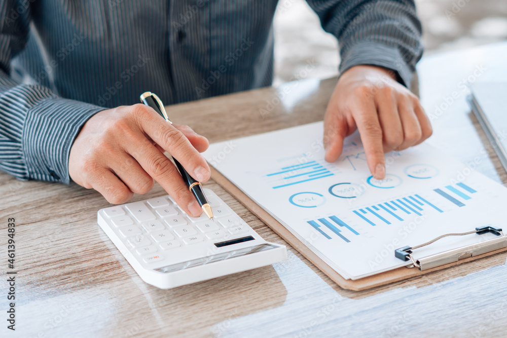 Close up hand of businessman or accountant hand holding pen working on calculator to calculate busin