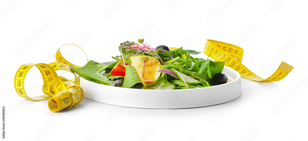 Plate with healthy salad and measuring tape on white background