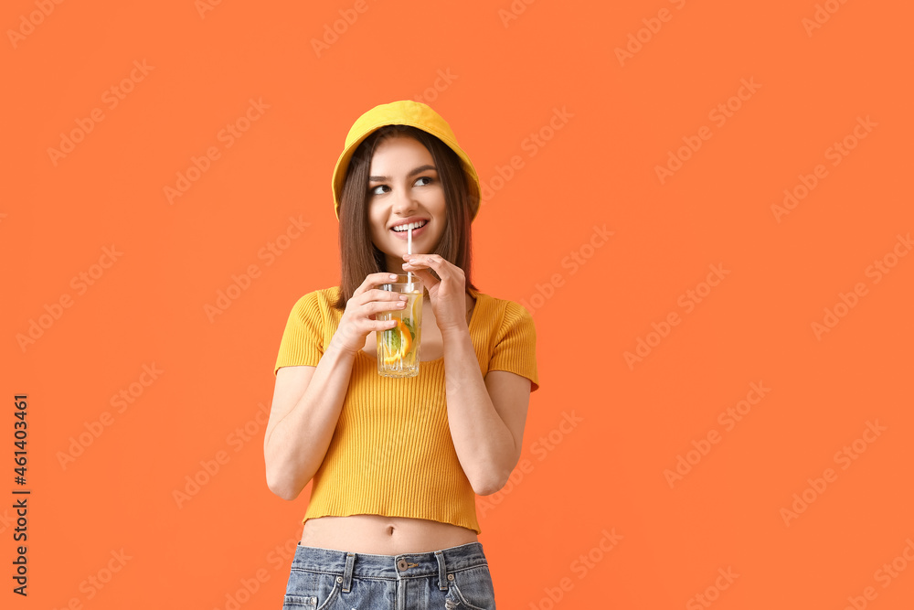 Beautiful young woman drinking fresh lemonade on color background