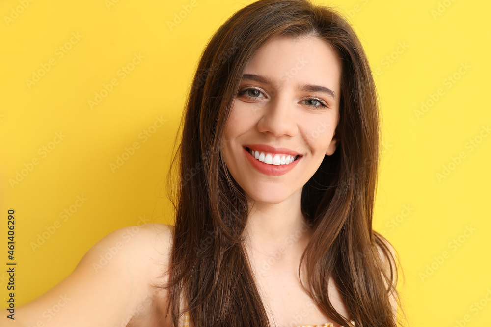 Stylish young woman taking selfie on color background