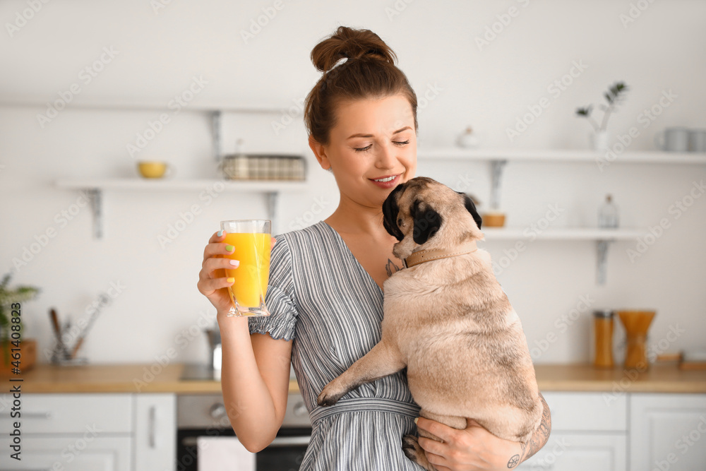 厨房里有可爱的哈巴狗和一杯果汁的年轻女人