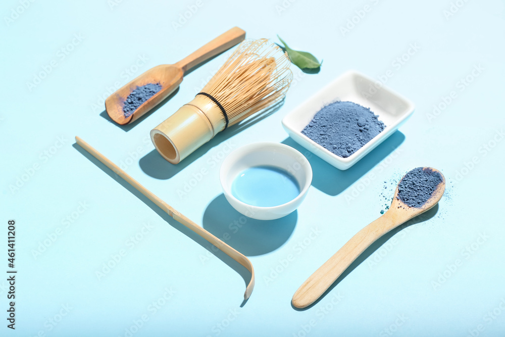 Composition with powdered blue matcha tea, chasen and chashaku on color background