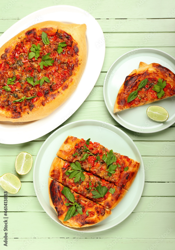 Plates with tasty Turkish Pizza on green wooden background