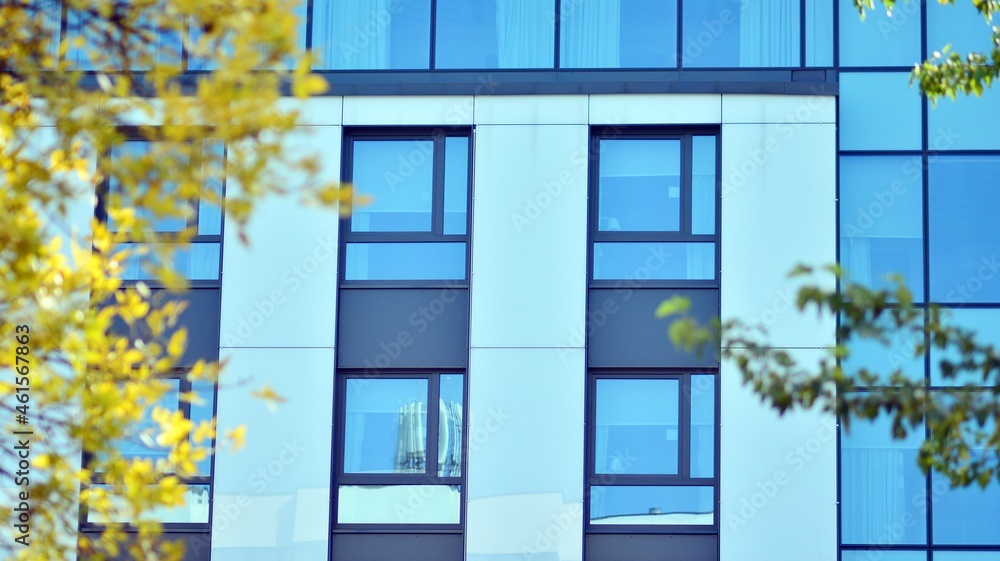 Inspiring view of the modern city. The wall of the building of glass and metal against trees. Corpor