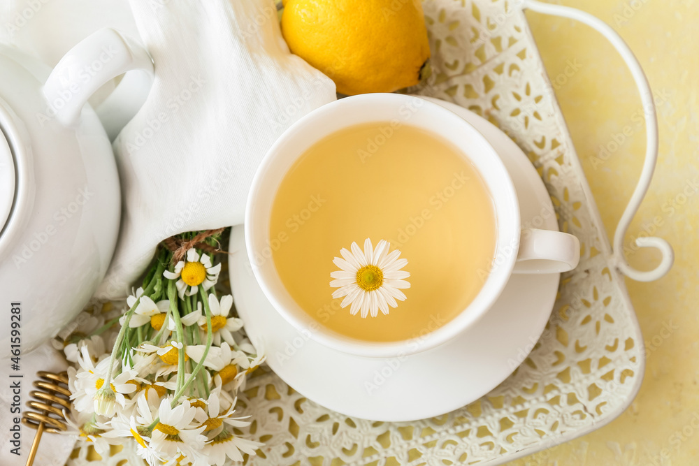 托盘上放着一杯美味的洋甘菊茶、鲜花和柠檬