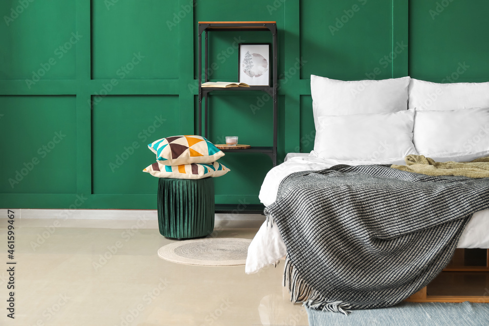 Double bed with cozy blanket in interior of green bedroom