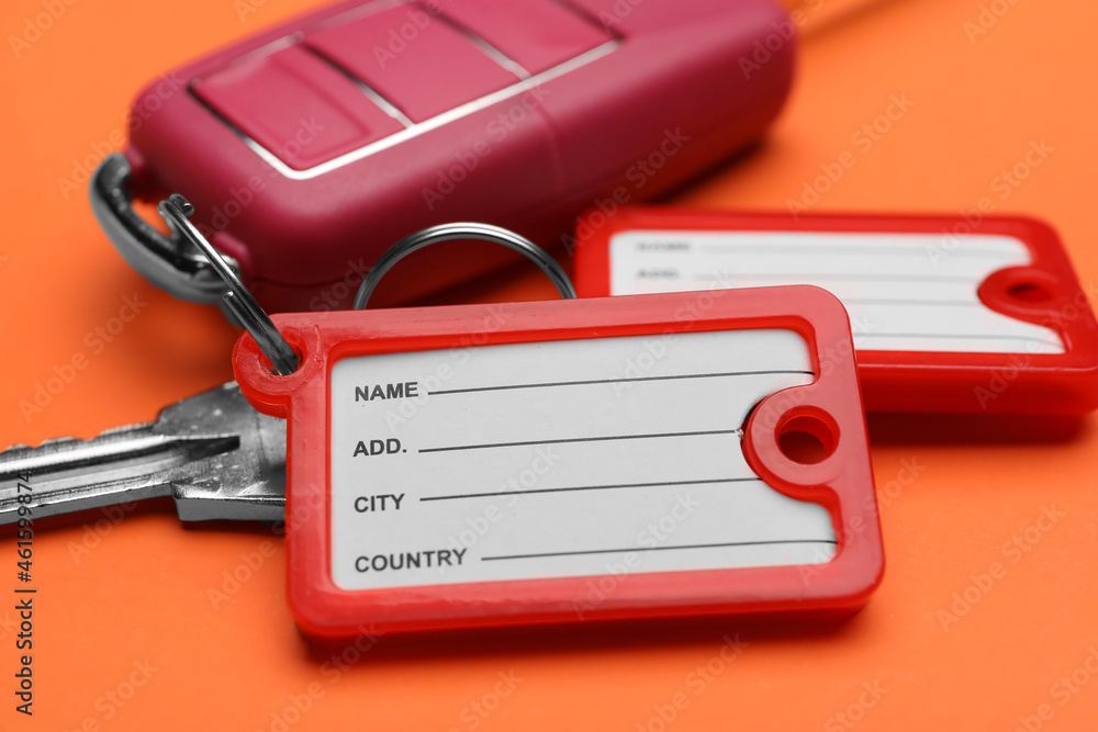 Different keys with plastic tags on orange background, closeup