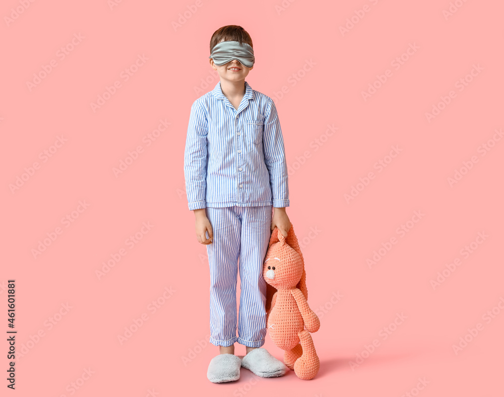 Little boy with sleep mask and toy on color background