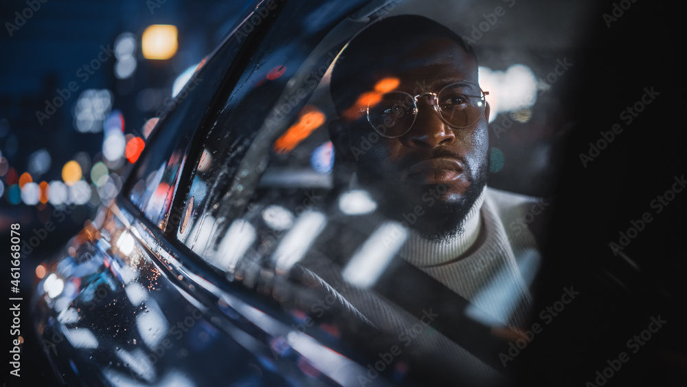 Stylish Black Man in Glasses is Commuting Home in a Backseat of a Taxi on a Rainy Night. Handsome Ma