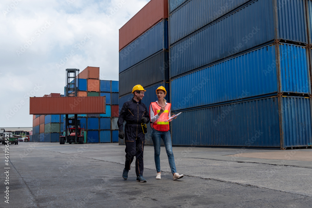 Industrial worker works with co-worker at overseas shipping container yard . Logistics supply chain 