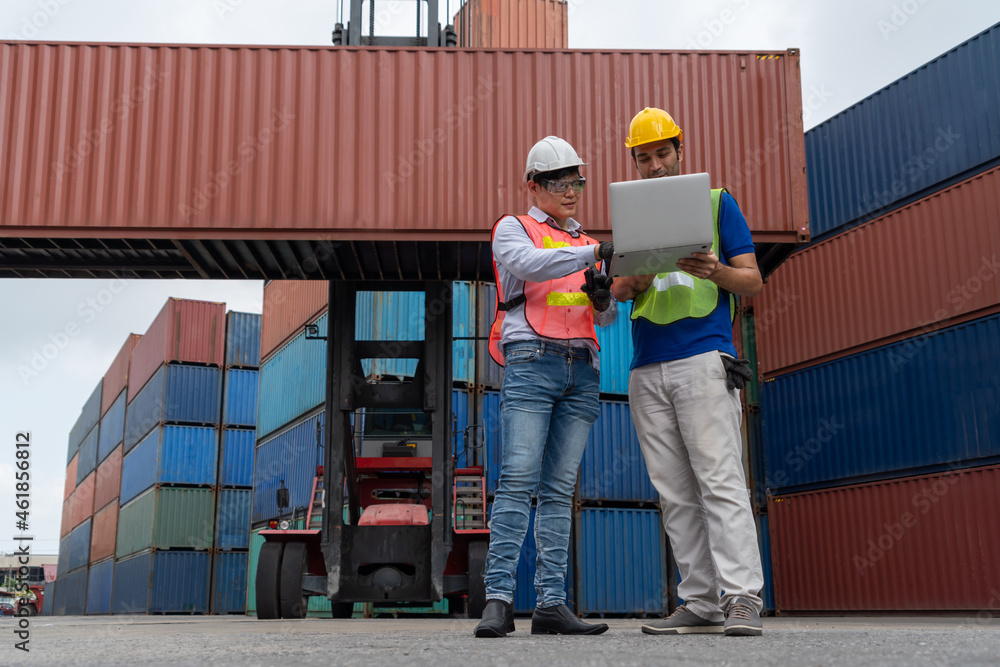 Industrial worker works with co-worker at overseas shipping container yard . Logistics supply chain 