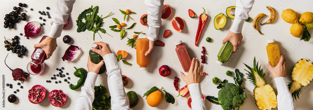 Flat-lay of human hands keeping bottles with fresh juices