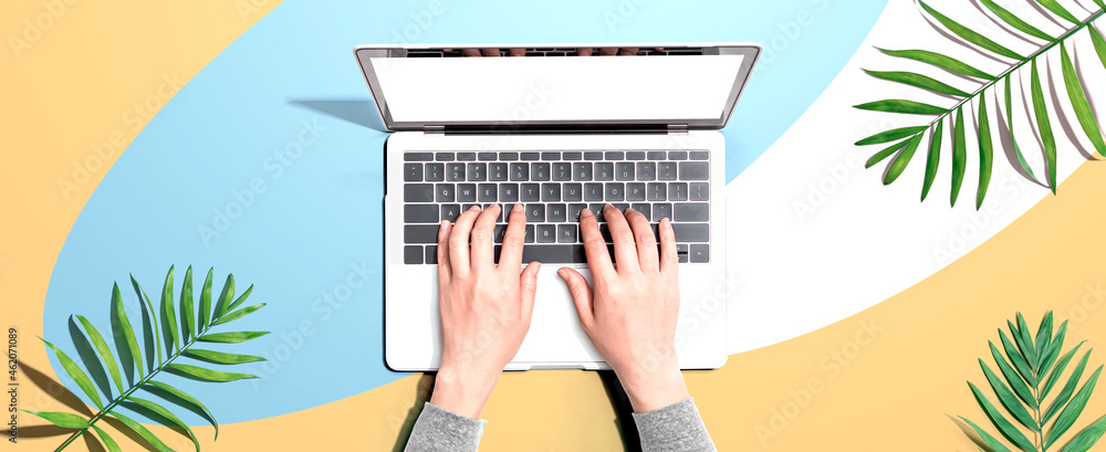 Person using a laptop computer with tropical leaves from above