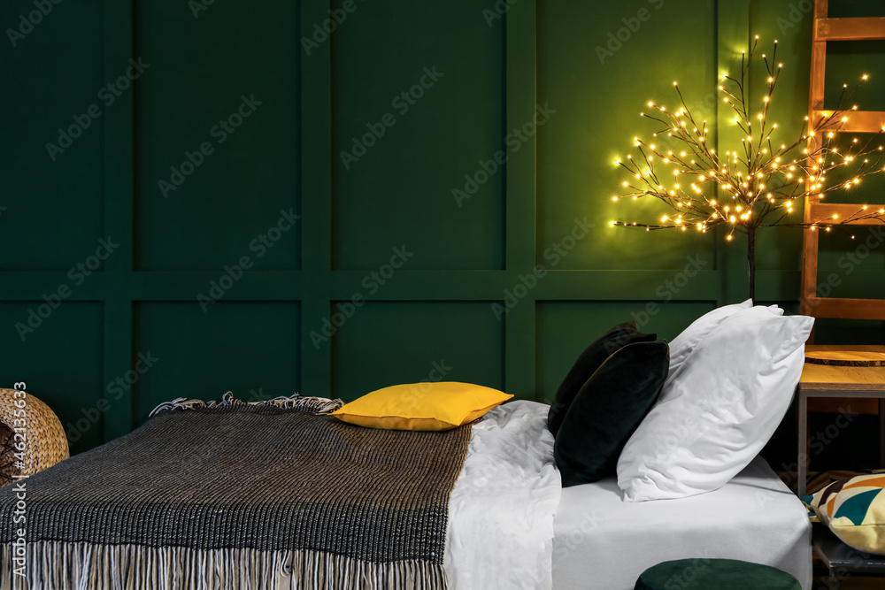 Modern interior of green bedroom with cozy bed and glowing lamp