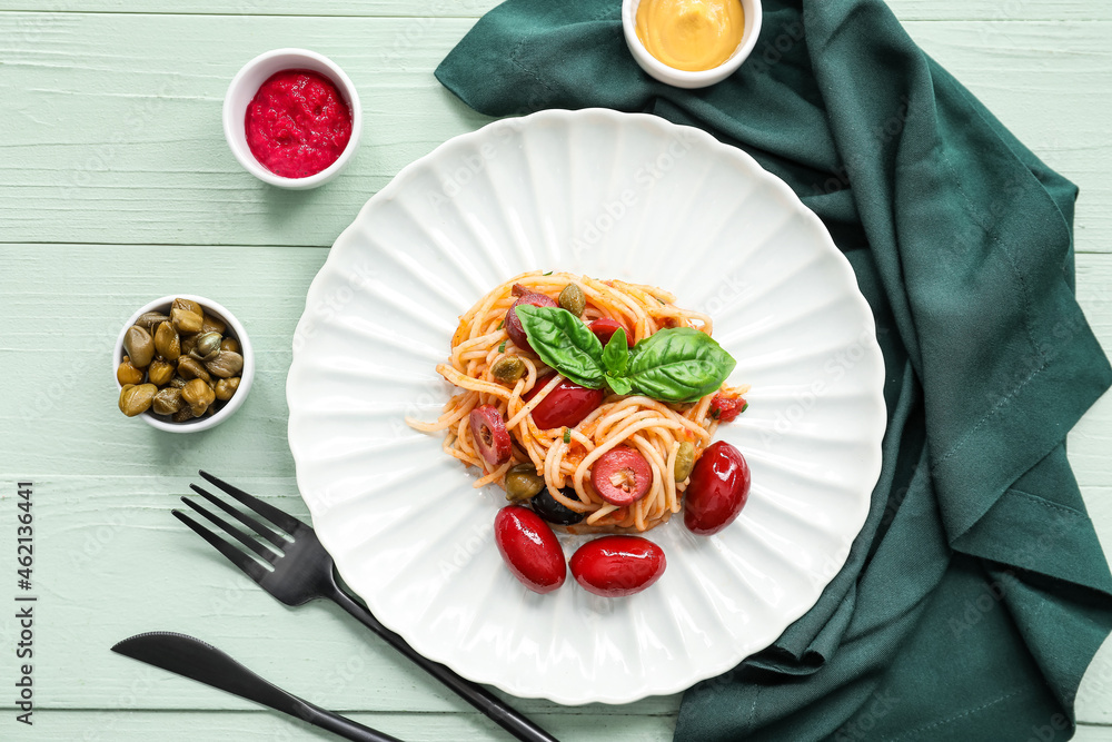 Plate of tasty Pasta Puttanesca and sauces on wooden background