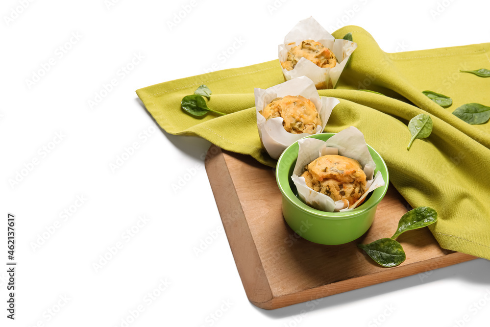 Wooden board with tasty spinach muffins on white background