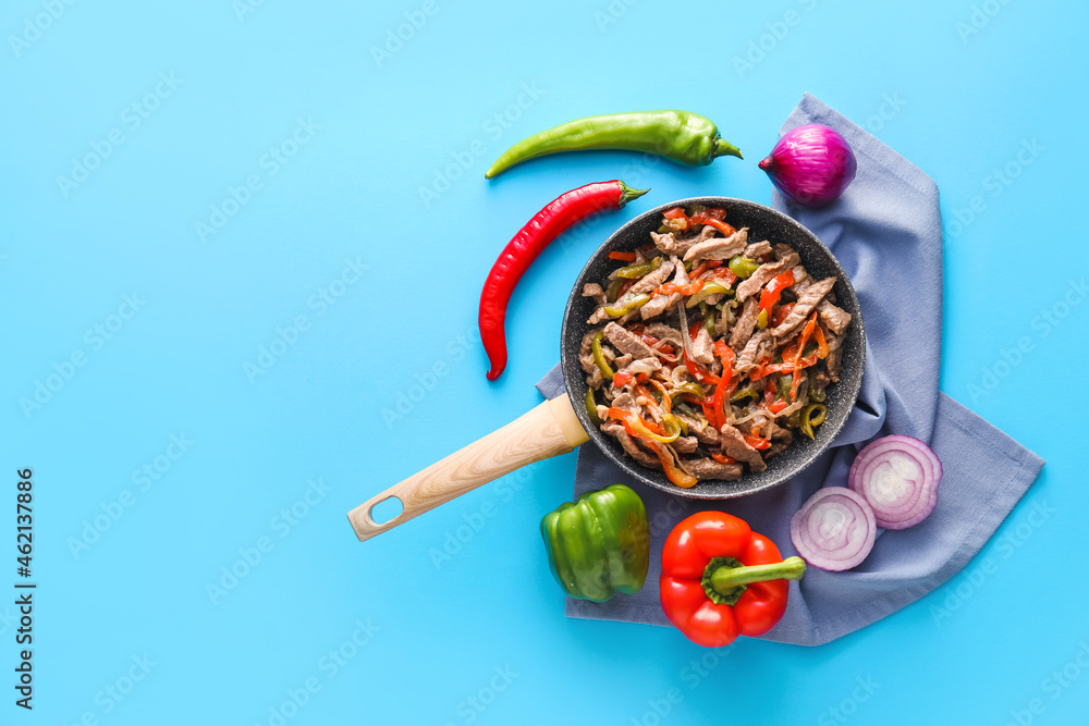 Frying pan with tasty Fajita and vegetables on color background