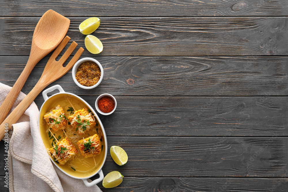 Baking dish with pieces of delicious Elote Mexican Street Corn and spices on black wooden background