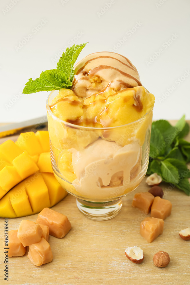 Bowl of delicious ice cream balls with caramels and mango on light background