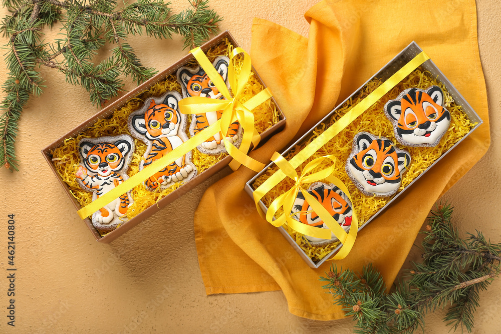 Cute cookies in shape of tiger for New Year 2022 in boxes on color background