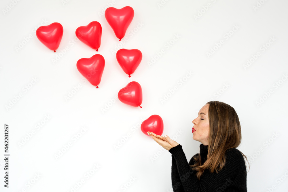 A woman blowing heart balloons