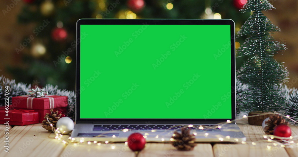 Laptop with green screen on screen, with christmas decorations and tree