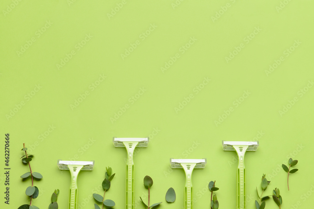 Safety razors and eucalyptus branches on green background, closeup