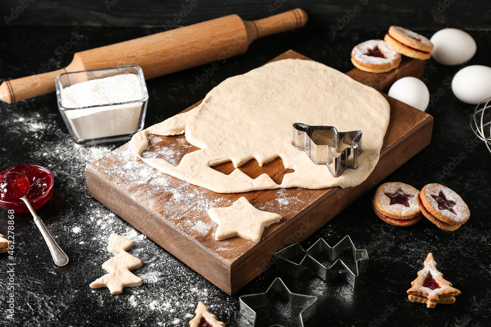 Preparing of tasty Linzer cookies on dark background