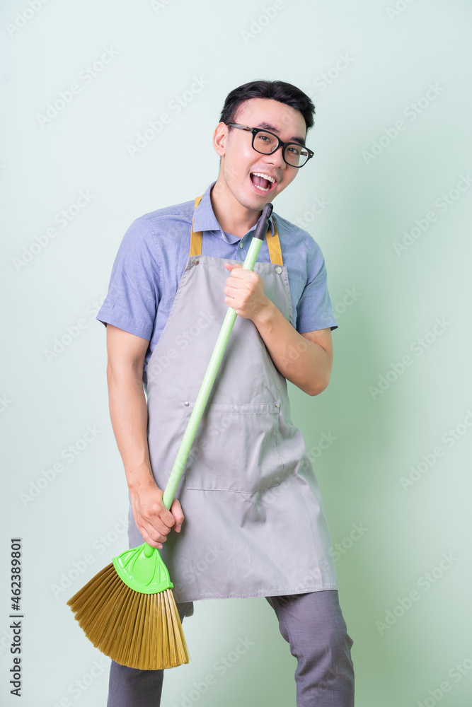 Young Asian man wearing apron posing on green background