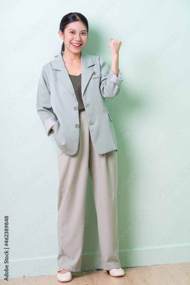 Young Asian businesswoman wearing green suit on green background