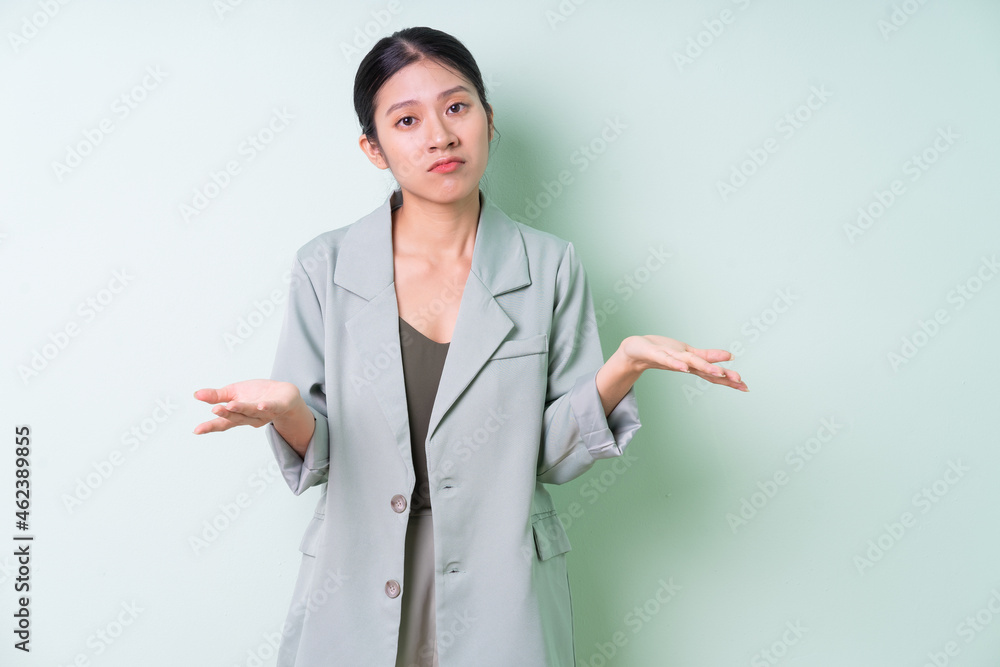 Young Asian businesswoman wearing green suit on green background