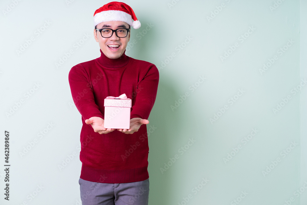 Young Asian man wearing christmas hat on green background