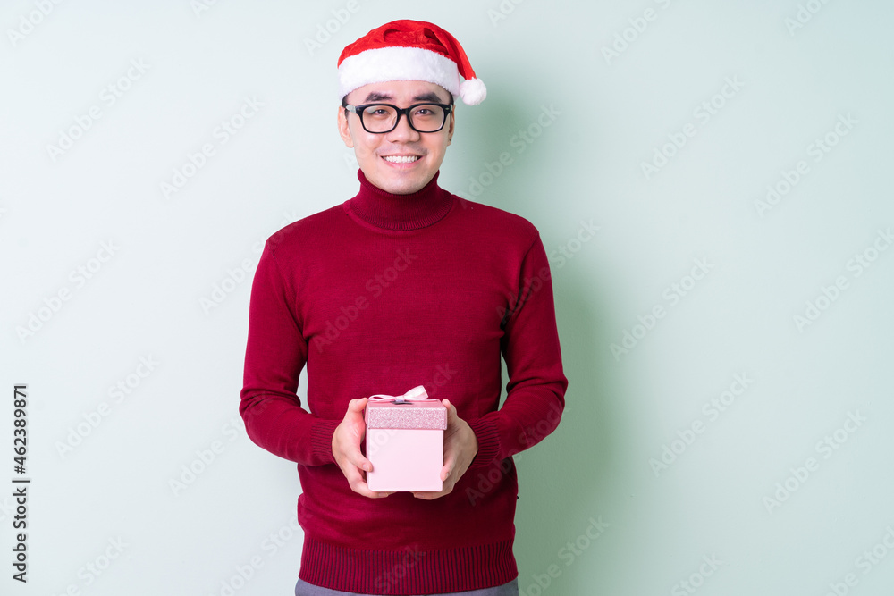 Young Asian man wearing christmas hat on green background