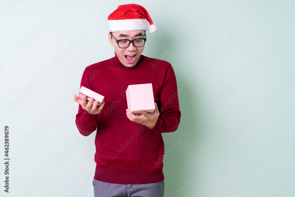 Young Asian man wearing christmas hat on green background