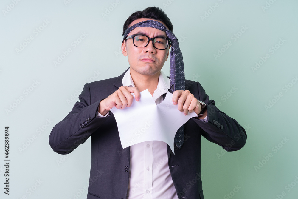 Young Asian businessman posing on green background