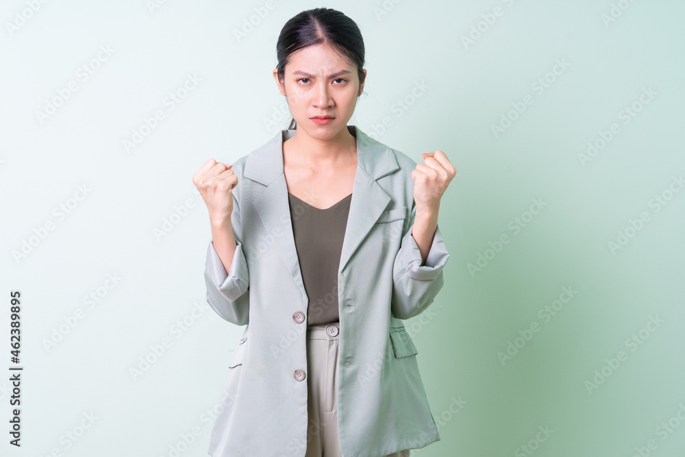 Young Asian businesswoman wearing green suit on green background