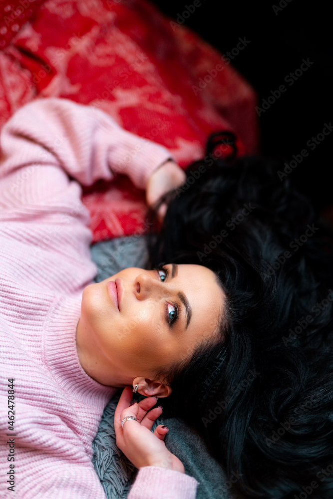 Woman in pink sweater laying on bed while posing to the camera. Portrait view. Happy New Year and me