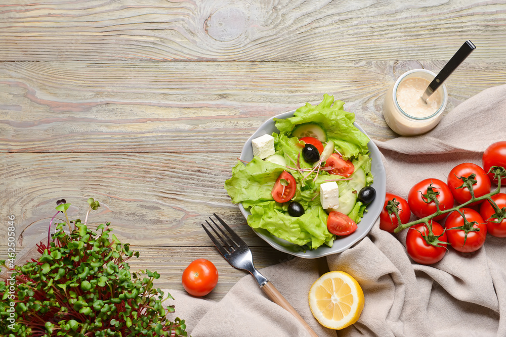 Plate with healthy salad with feta cheese and olives on wooden background